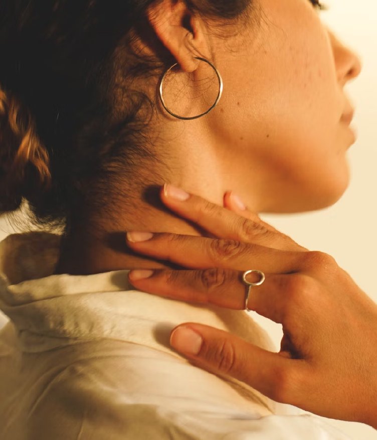 Jeune femme portant des boucles d'oreilles, une main sur la nuque.